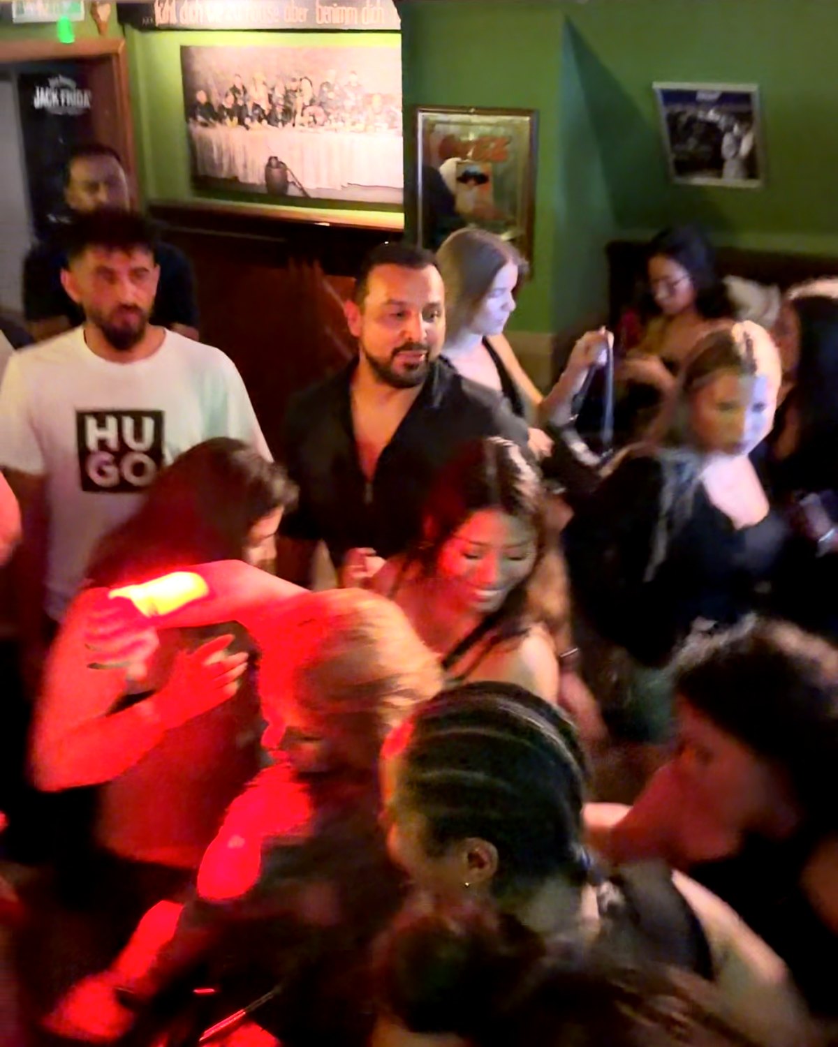 Packed dance floor in red light at a Medianoche Latin night
